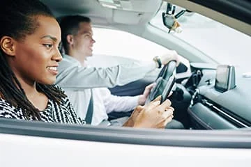Conducteur au volant et passagère à l’avant d’une voiture.