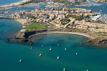 Vue aérienne d’un port et de plages au bord d’une mer turquoise.